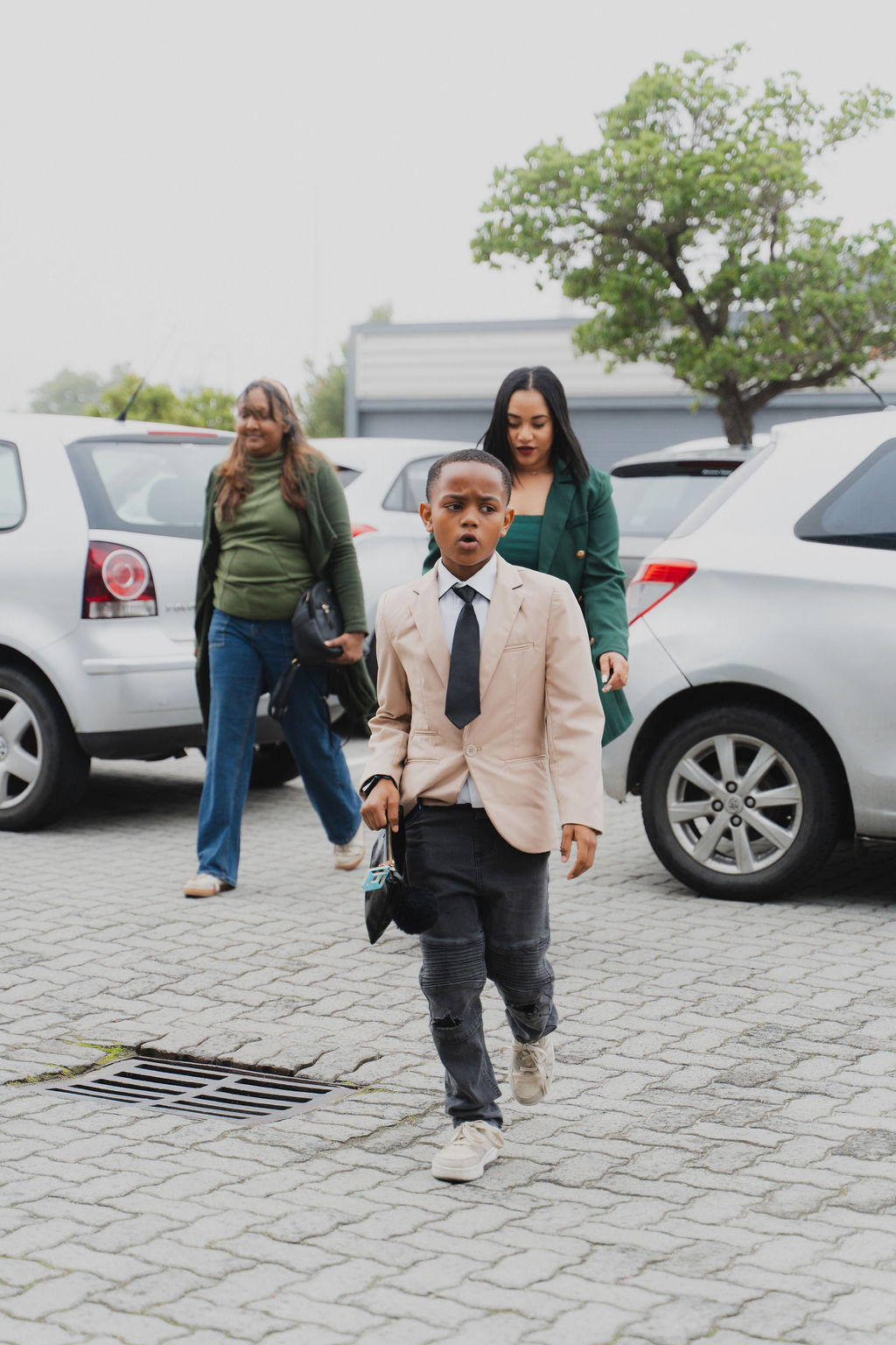 Child walking into church wearing a suit with a parent behind